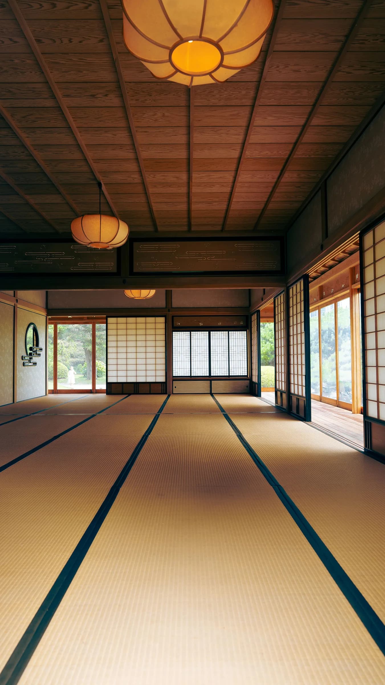 A tatami room with warm lamps and sliding doors opening onto greenery