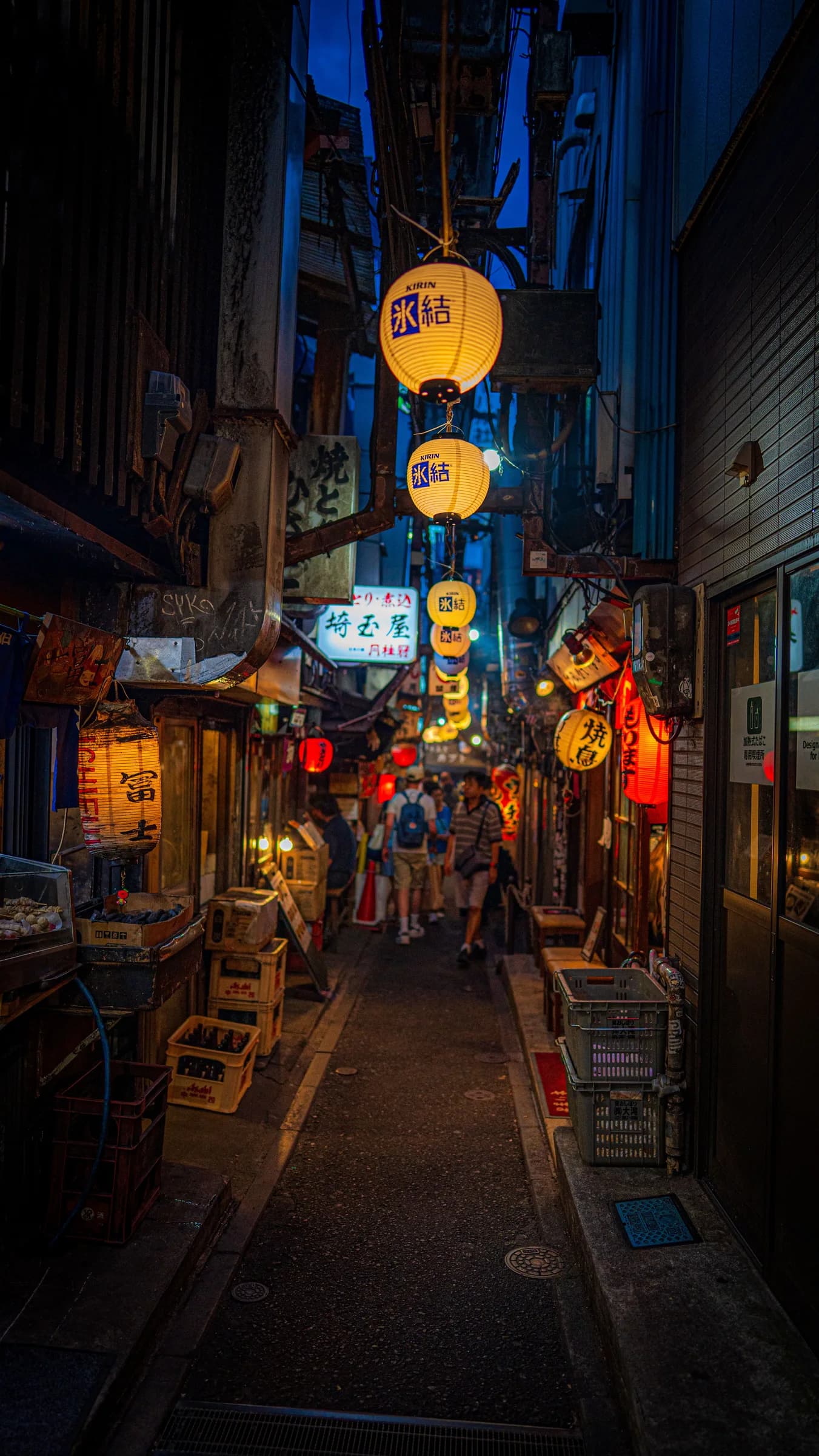 Yellow and red lanterns above a narrow alley lined with small bars and restaurants
