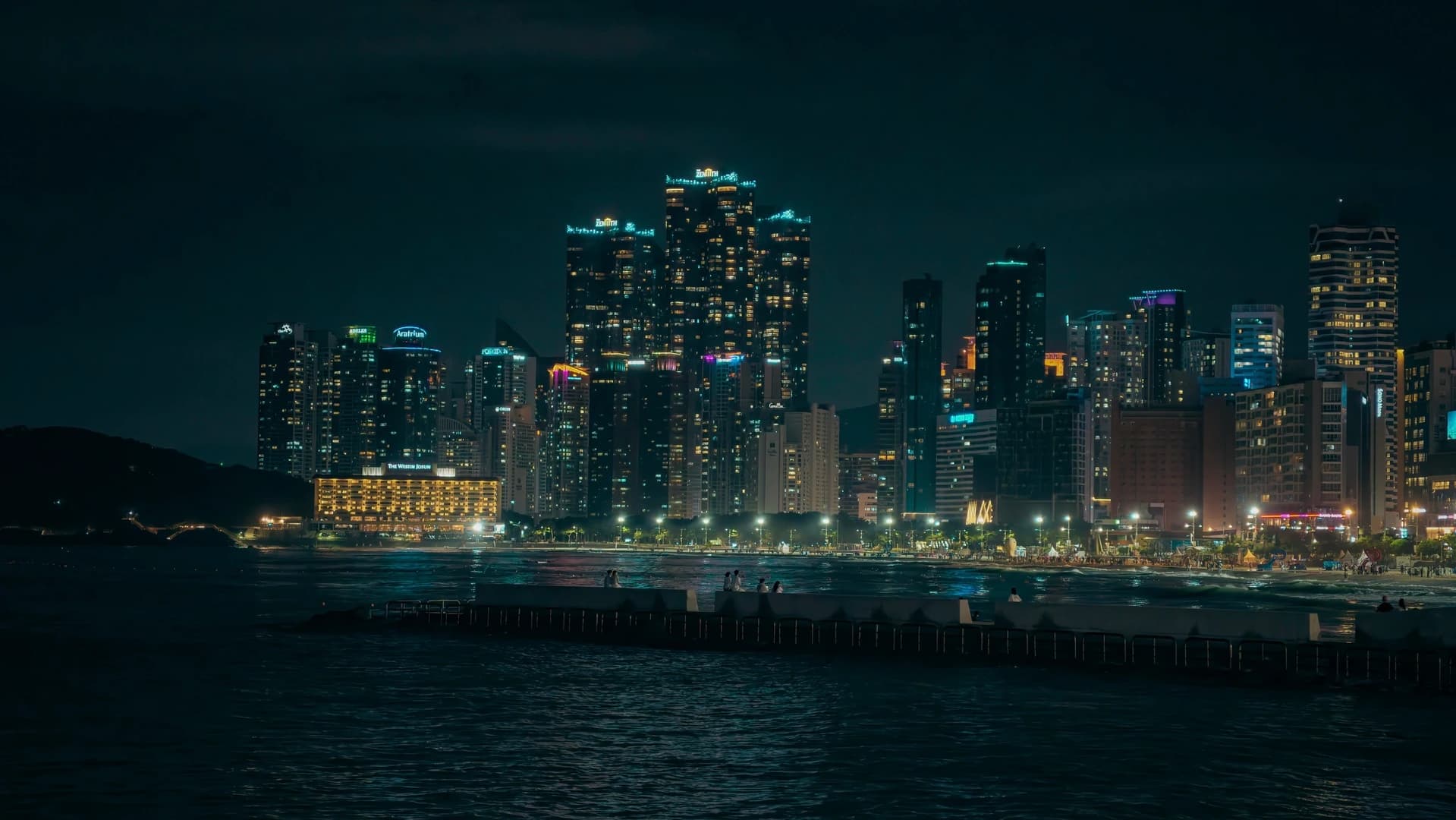 I grattacieli illuminati di Busan affacciati sul mare di notte